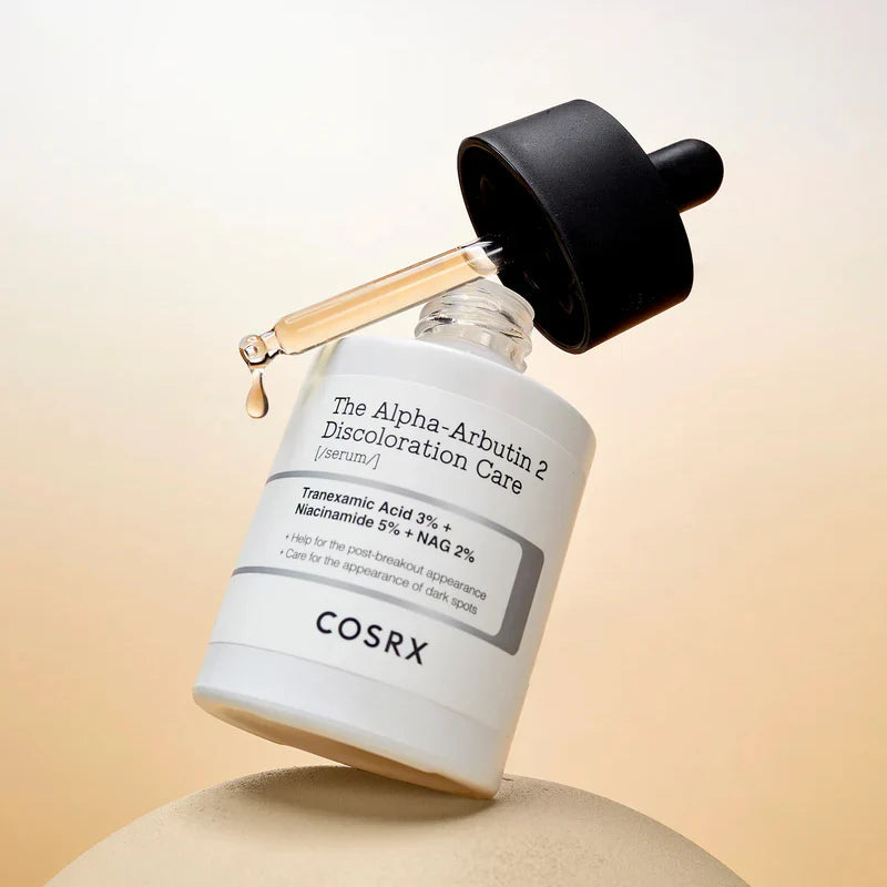 COSRX Alpha-Arbutin 2 serum in a lifestyle skincare flat-lay setting